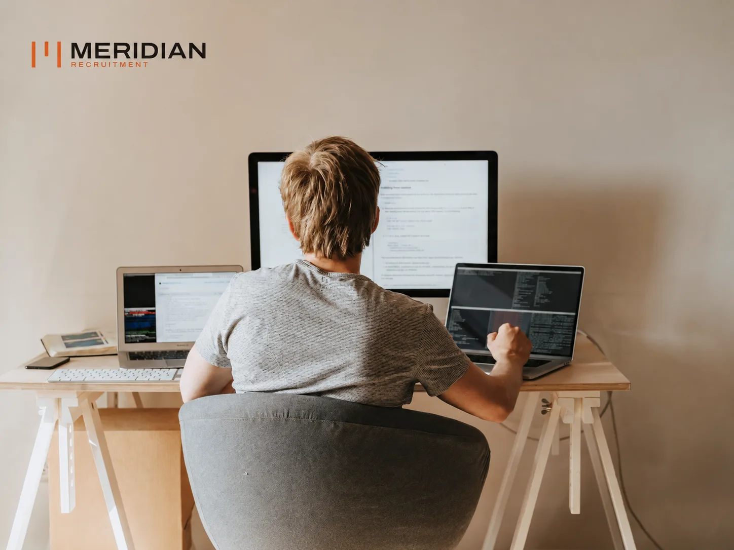 Engineer working across a monitor and two laptops at a desk
