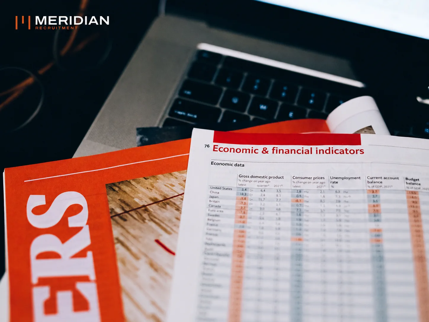 Economic and financial indicator tables laid over a laptop